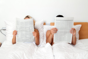 Wollen sie wissen ob es stimmt was sie lesen? Paar im Bett liest Zeitung. Information und Nachrichten